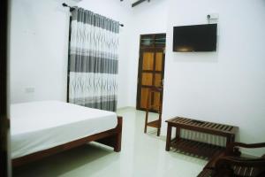 1 dormitorio con 1 cama, TV y mesa en Sunset Villa en Tissamaharama