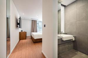 uma casa de banho com um lavatório, uma cama e um espelho. em Hotel Cielo em Siheung