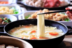 a person is stirring a bowl of soup with chopsticks at ART Hotel Oita in Oita