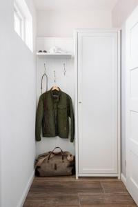 a closet with a green jacket and a bag at Reetdorf Geltinger Birk Künstlerkate Sandkoppel in Nieby