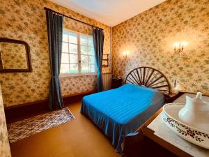 a bedroom with a blue bed and a window at Maison Lomprère in Fichous-Riumayou
