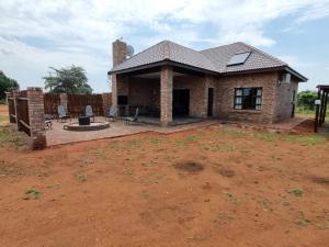 a brick house with a patio and a yard at Sondela Nature Reserve & Spa Chalets in Bela-Bela