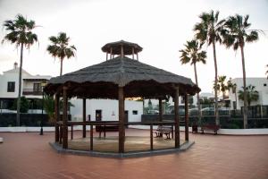 een houten paviljoen met banken en palmbomen bij Malvasía House in Costa Teguise