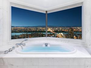 a bath tub in a bathroom with a large window at Hotel Hankyu International in Osaka