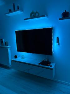 a living room with a television in a blue room at Perle rare « Le Cosy de CDG » in Le Blanc-Mesnil