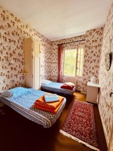 a bedroom with two beds and a window and a rug at Maison Lomprère in Fichous-Riumayou