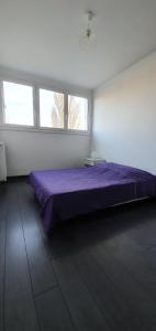 um quarto com uma cama roxa e 2 janelas em Chambre chez l'habitant - Appartement lumineux - Gare à 2 arrêts de tram em Fleury-les-Aubrais