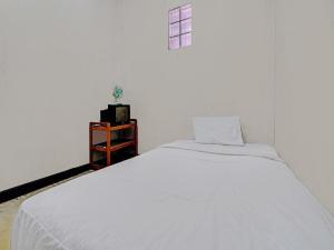Cama blanca en habitación blanca con ventana en OYO Life 92709 Kost Teras Cikapundung Syariah en Bandung