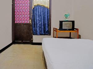 um quarto com uma cama, uma televisão e uma porta em OYO Life 92709 Kost Teras Cikapundung Syariah em Bandung