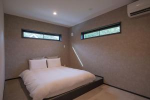 a bedroom with a white bed and two windows at VACILANDO in Fujikawaguchiko