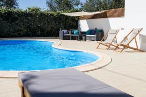 uma piscina com duas espreguiçadeiras ao lado em Casa do Avô Serra em Leiria