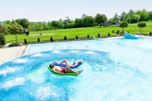 鲁多尔施塔特Ferienhäuser Saalemaxx的两人在游泳池里木筏上骑着