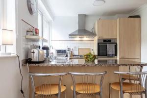a kitchen with a counter with three bar stools at Peaceful Renovated 5BDR house wgarden in London