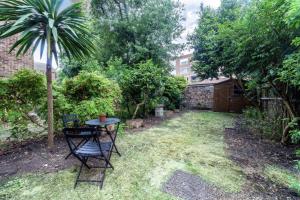 a small yard with a table and chairs and a palm tree at Peaceful Renovated 5BDR house wgarden in London