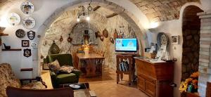 uma sala de estar com televisão numa parede de pedra em La grotta di NiMa em Pretoro