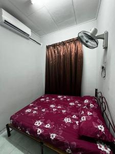 een slaapkamer met een bed met paarse lakens en een ventilator bij HOMESTAY NO.45 in Jitra