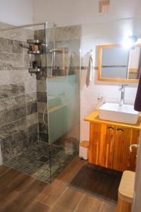 a bathroom with a glass shower and a sink at Le Ti' Case en bord de plage. in Case-Pilote