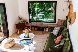 ein Wohnzimmer mit einem grünen Sofa und einem großen TV in der Unterkunft Dans les Arbres in Lanta