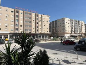 un gran edificio con coches estacionados en un estacionamiento en Palmeraies vacances Tunis, en La Marsa