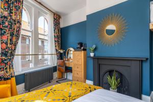 een slaapkamer met een blauwe muur, een open haard en een spiegel bij Duke of Cumberland in Whitstable