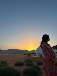 a woman standing in the desert looking at the sunset at Bubble camp 2 in Wadi Rum