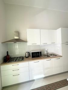 uma cozinha branca com um lavatório e um micro-ondas em Conte125 em Cinisi