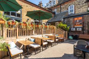 un patio con mesas, sillas y una sombrilla en Duke of Cumberland, en Whitstable