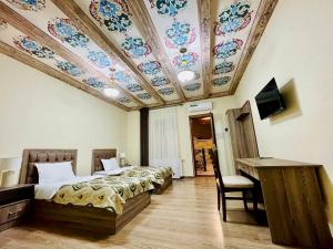 um quarto com 2 camas e um tecto com flores em Mevlana Hotel em Samarkand