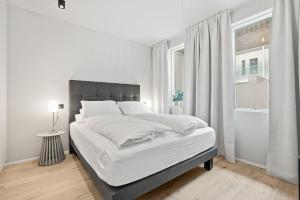 a white bedroom with a large bed and a window at Brand New Downtown Harbor Apartment in Reykjavík