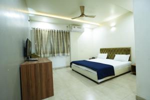 a bedroom with a bed and a television in it at Hotel Anand in Kolhapur