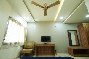 a living room with a ceiling fan and a tv at Hotel Anand in Kolhapur