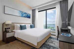 a bedroom with a large bed and a large window at Citadines Marina Halong in Ha Long