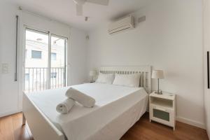 a white bedroom with a large white bed and a window at Beach Villa Cristina by HHBCN in Castelldefels +37 photos