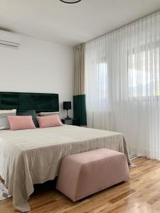 a white bedroom with a large bed with pink pillows at VILA SLAVA in Vrnjačka Banja