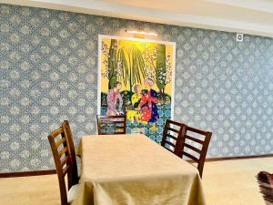 uma sala de jantar com uma mesa e cadeiras e um quadro em Mevlana Hotel em Samarkand