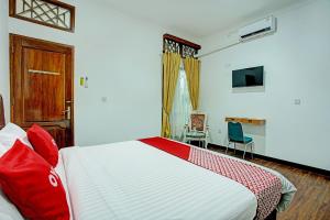 a bedroom with a bed and a desk and a television at Capital O 92990 Nena Kostel Syariah in Padang