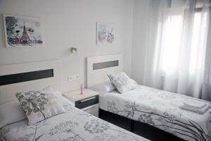 1 dormitorio con 2 camas y ventana en Zubia Home Portugalete - Impecable- 3 min metro Bilbao, en Portugalete