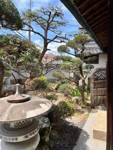 和風庭園豪邸 في أوساكا: وجود مزهرية على طاولة حجرية في حديقة
