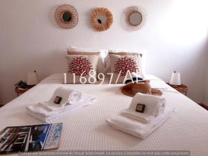 ein weißes Bett mit Handtüchern und Spiegeln an der Wand in der Unterkunft Beach Apartment Terrace in Vilamoura + 19 Fotos