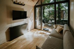 a living room with a couch and a television at Slowood Cabins in Balatonszepezd