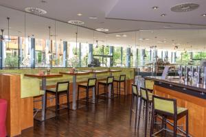 un bar con taburetes en un restaurante con ventanas en Trans World Hotel Donauwelle, en Linz