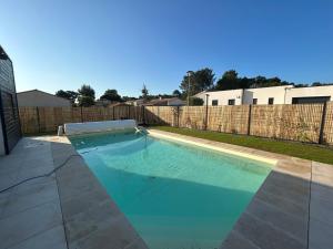 a swimming pool with blue water in a backyard at La Forêt d'Armotte villa 16 By Avecoeur in Saint-Augustin