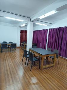 Habitación con mesas, sillas y cortinas moradas. en Hotel 7 Eleven, en Dirang Dzong