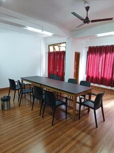 a table and chairs in a room with red curtains at Hotel 7 Eleven in Dirang Dzong