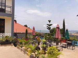 eine Terrasse mit Tischen, Stühlen und Sonnenschirmen in der Unterkunft Rosa Negra Uganda in Kigo