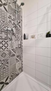 a bathroom with a shower and a tile wall at Finnem Rentals Zíkova in Prague