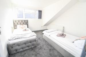 two beds in a room with white walls at Remarkable 4-Bed House in Bradford in Bradford