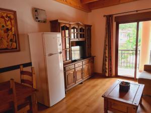 eine Küche mit einem Kühlschrank, einem Tisch und einem Fenster in der Unterkunft Sierra de Cazorla in Arroyo Frio