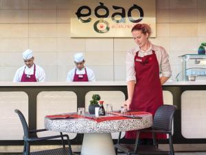 una mujer parada frente a una mesa en un restaurante en Leonardo Cypria Bay en Pafos