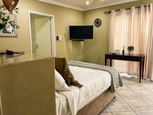een slaapkamer met een bed en een flatscreen-tv bij Telestai Guest House in White River